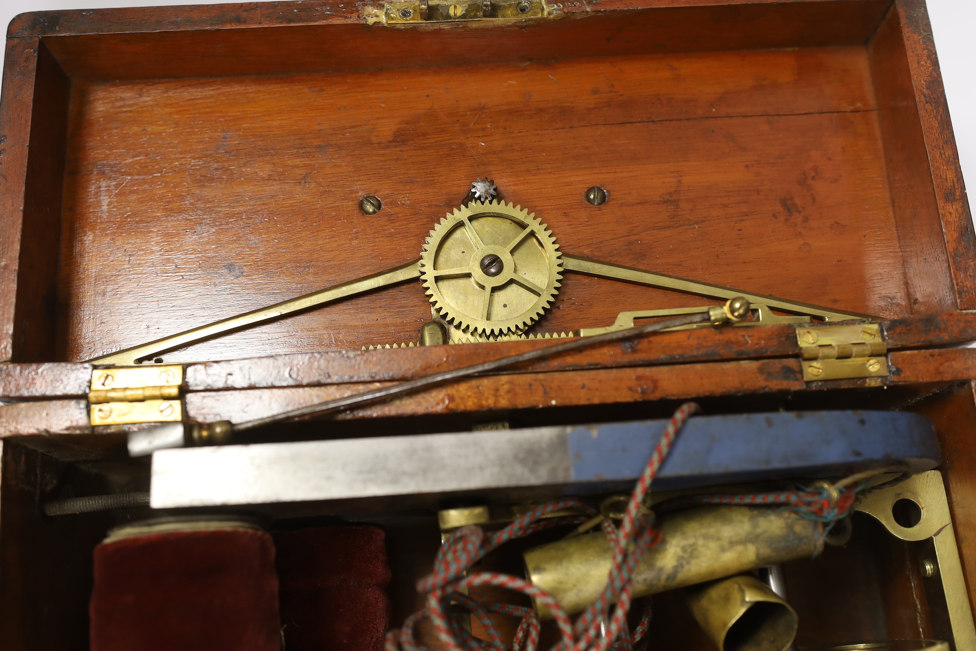 A Magneto electric shock machine in a mahogany case with output gauge to lid and built-in drawer containing a range of alternative fittings and implements with ebonised handles, lock with original key, 16.5cm high, 30cm
